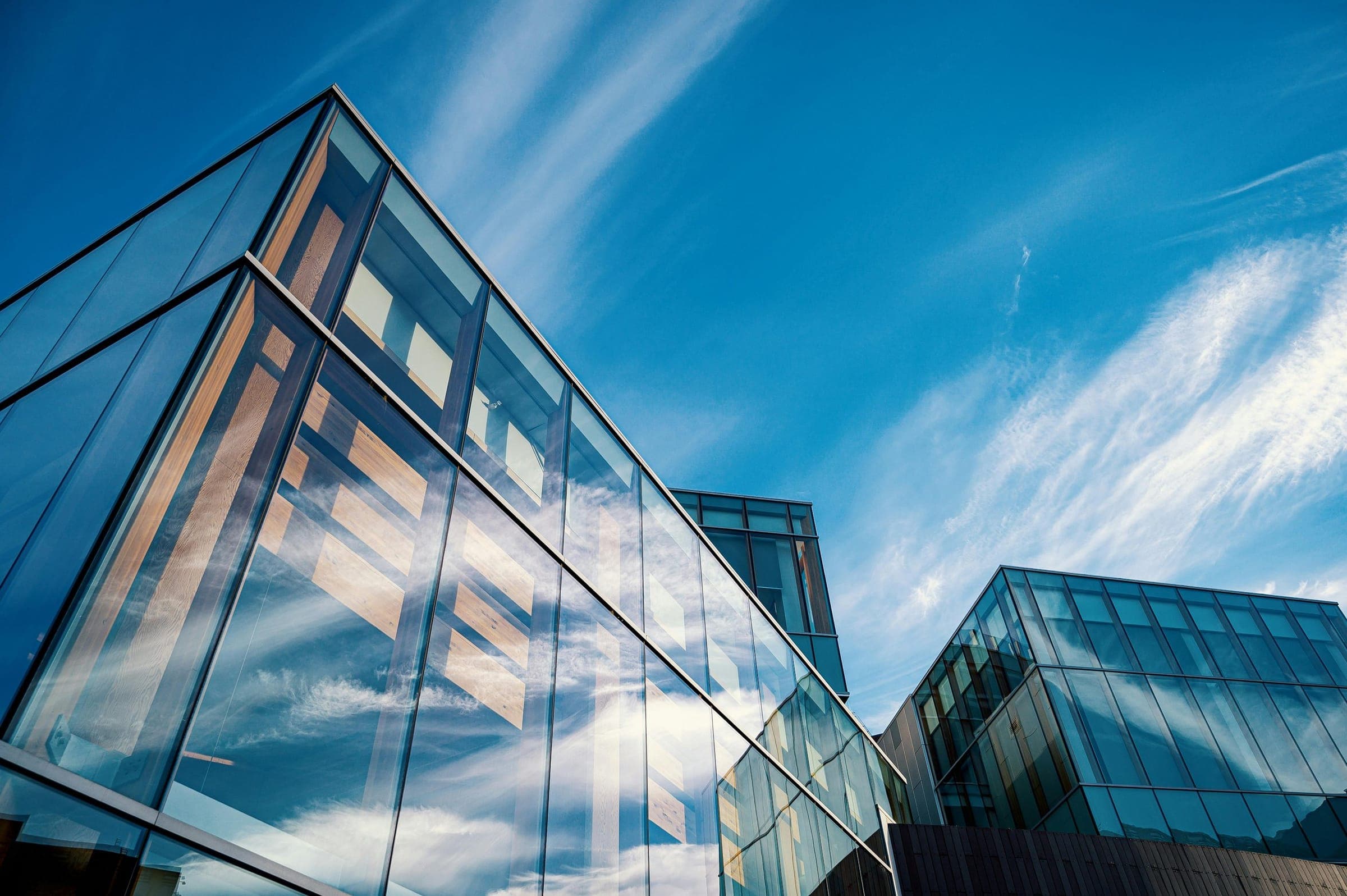 Glass office tower reflecting a blue sky